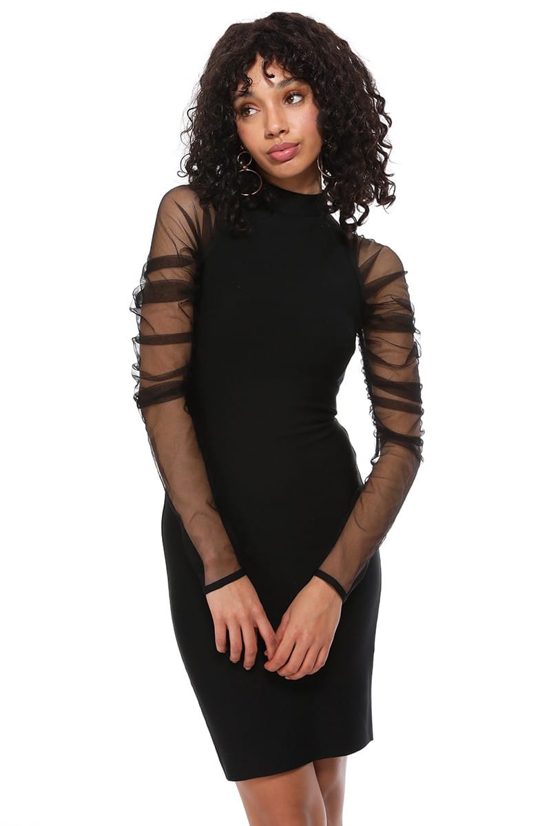 A woman modeling a black bodycon mini dress with sheer long sleeves featuring horizontal mesh cutouts, posed against a solid white background.