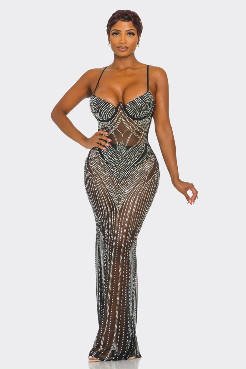 Woman wearing a black and gold beaded evening gown on a white background