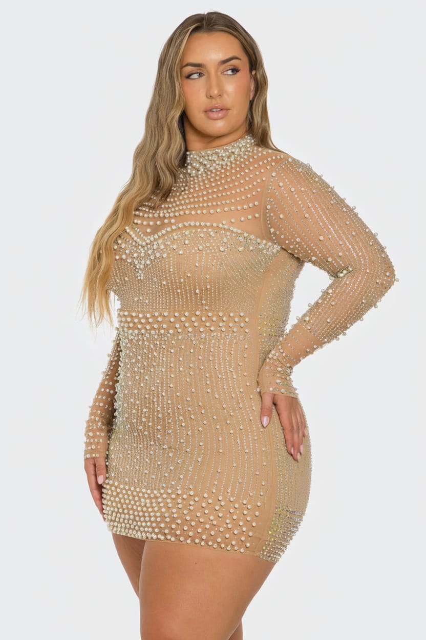 A woman modeling a sheer beige long-sleeve mini dress covered in rows of small pearl-like beads against a light gray studio background.