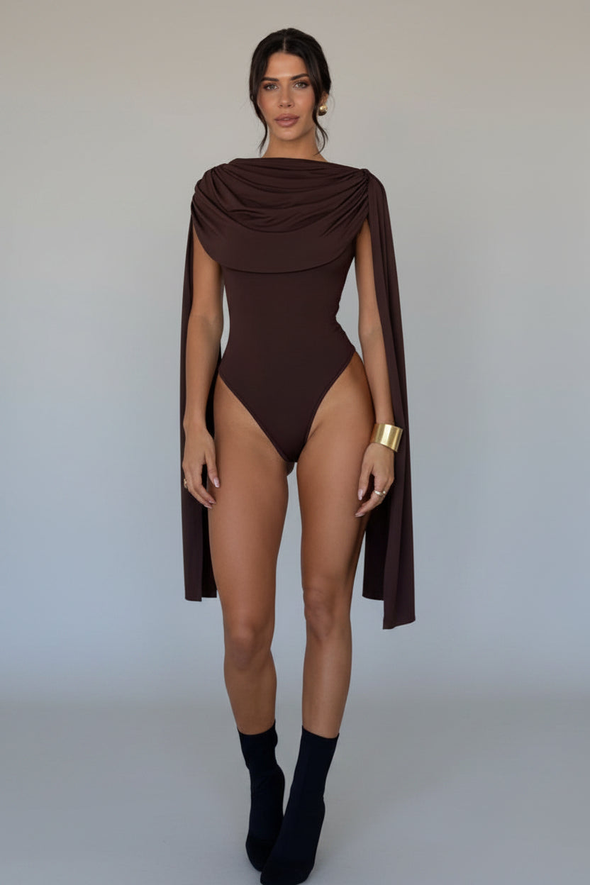 Woman wearing a brown bodysuit with a cape against a white background