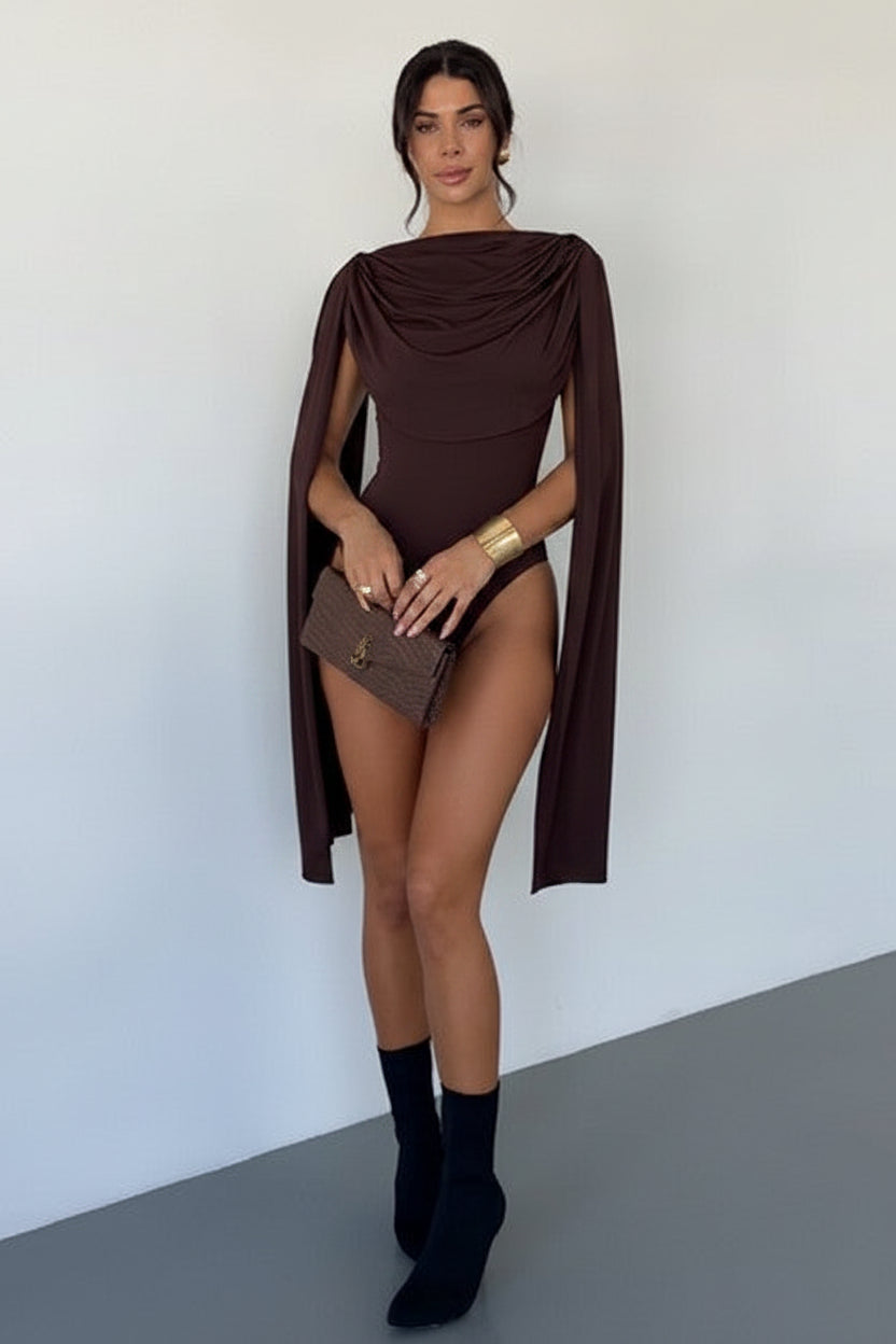 Woman wearing a brown caped outfit with black boots against a white background