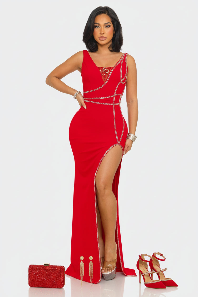 A woman modeling a bright red sleeveless maxi gown with a high thigh slit, embellished with silver chain details and a jeweled neckline, set against a plain light gray background.
