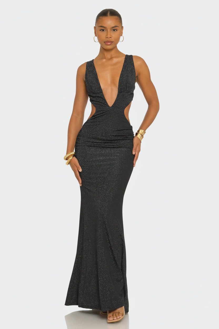 A woman modeling a dark charcoal gray sleeveless maxi dress with a plunging V-neckline, side cutouts, and a fitted mermaid silhouette against a light gray studio background.
