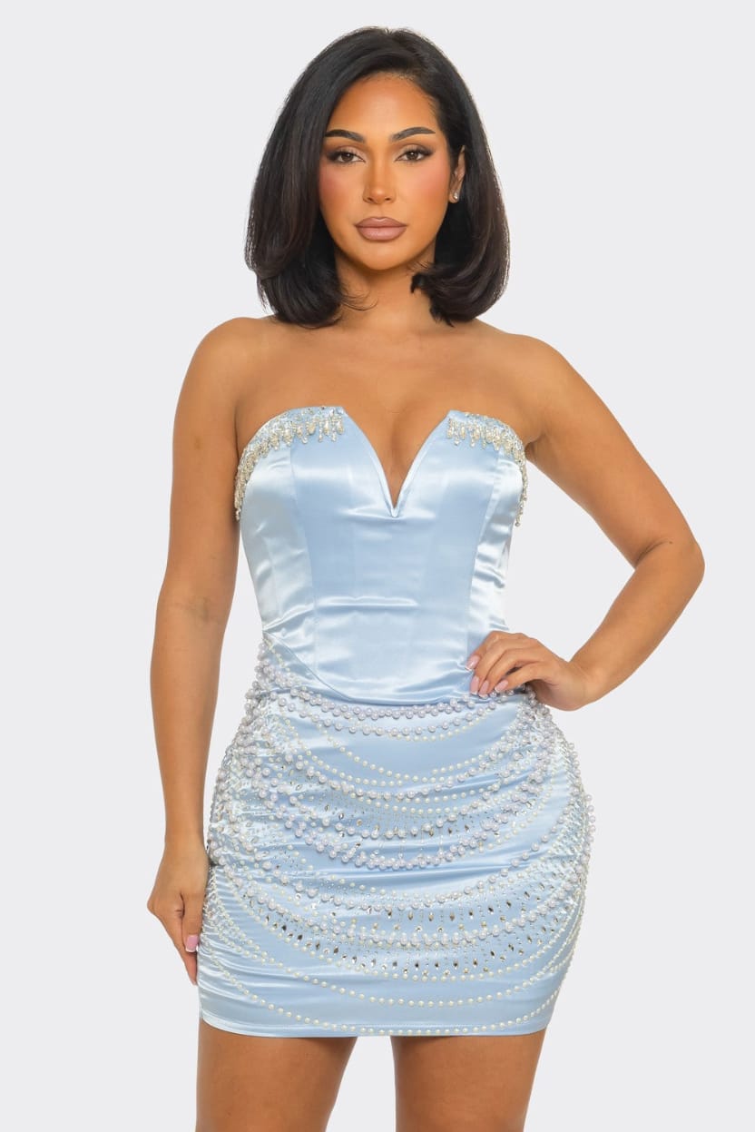 Woman wearing a light blue strapless dress with sequin embellishments on a white background