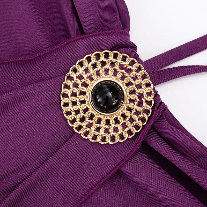 Close-up of a purple garment with a gold and black decorative brooch on a white background