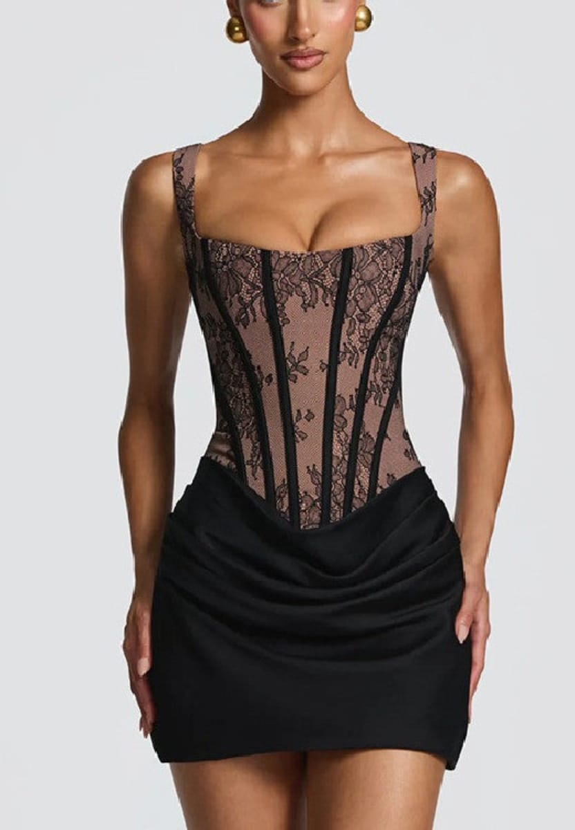 A model wearing a black corset-style mini dress with sheer floral lace panels and a ruched black skirt, shown against a light gray studio background.