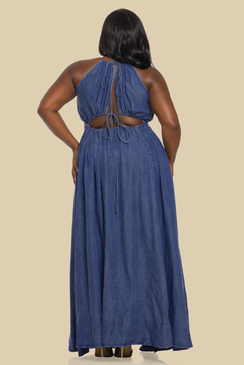 Woman wearing a blue denim dress with cut-out back on a beige background