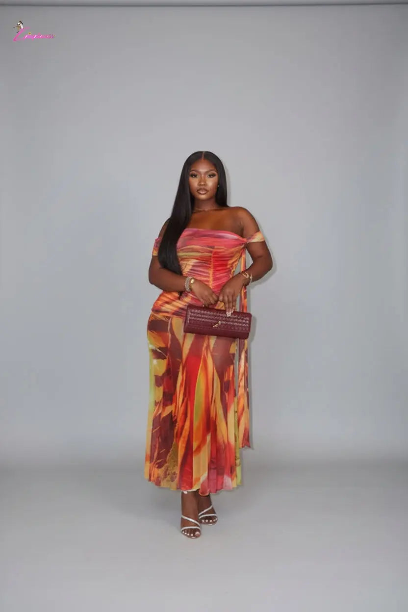 Woman in a colorful dress holding a red handbag indoors.