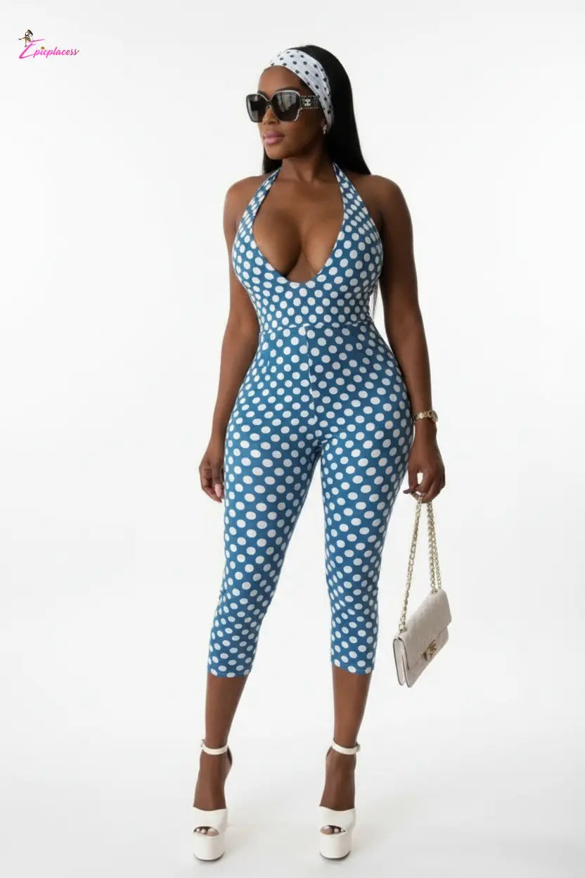 Model wearing retro polka dot halter jumpsuit in blue and white on white studio background