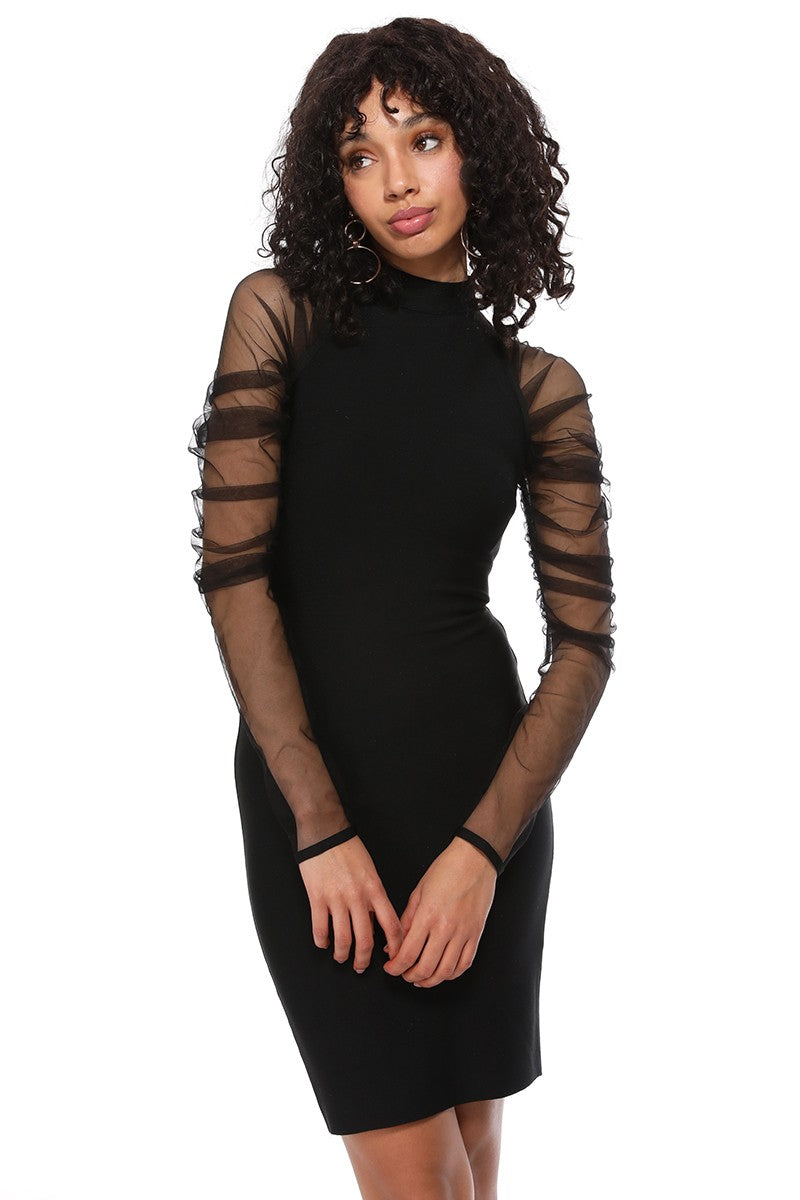A woman modeling a black bodycon mini dress with sheer long sleeves featuring horizontal mesh cutouts, posed against a solid white background.