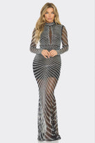 A woman modeling a long-sleeve, high-neck, floor-length gown covered in silver rhinestones over a sheer black mesh fabric, set against a plain light gray background.