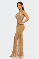 Woman wearing a gold beaded dress with fringe on a white background
