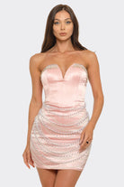 Woman wearing a pink strapless dress with lace details on a white background