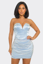 Woman wearing a light blue strapless dress with sequin embellishments on a white background