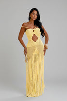 Woman wearing a yellow crochet dress with cut-out design outdoors.