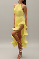 Woman in a yellow dress standing next to a table with yellow flowers and candles.