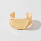 Gold cuff bracelet on a beige background