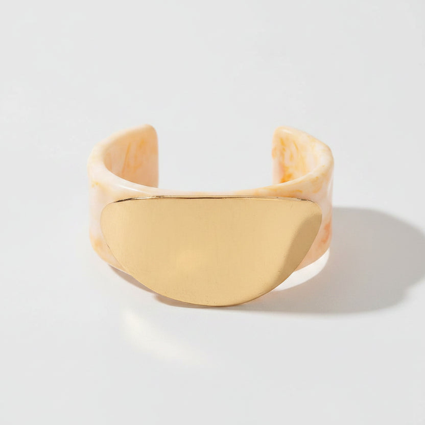 Gold cuff bracelet on a beige background
