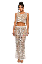 Woman wearing a white crochet top and skirt set on a white background