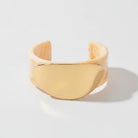 Gold cuff bracelet on a beige background