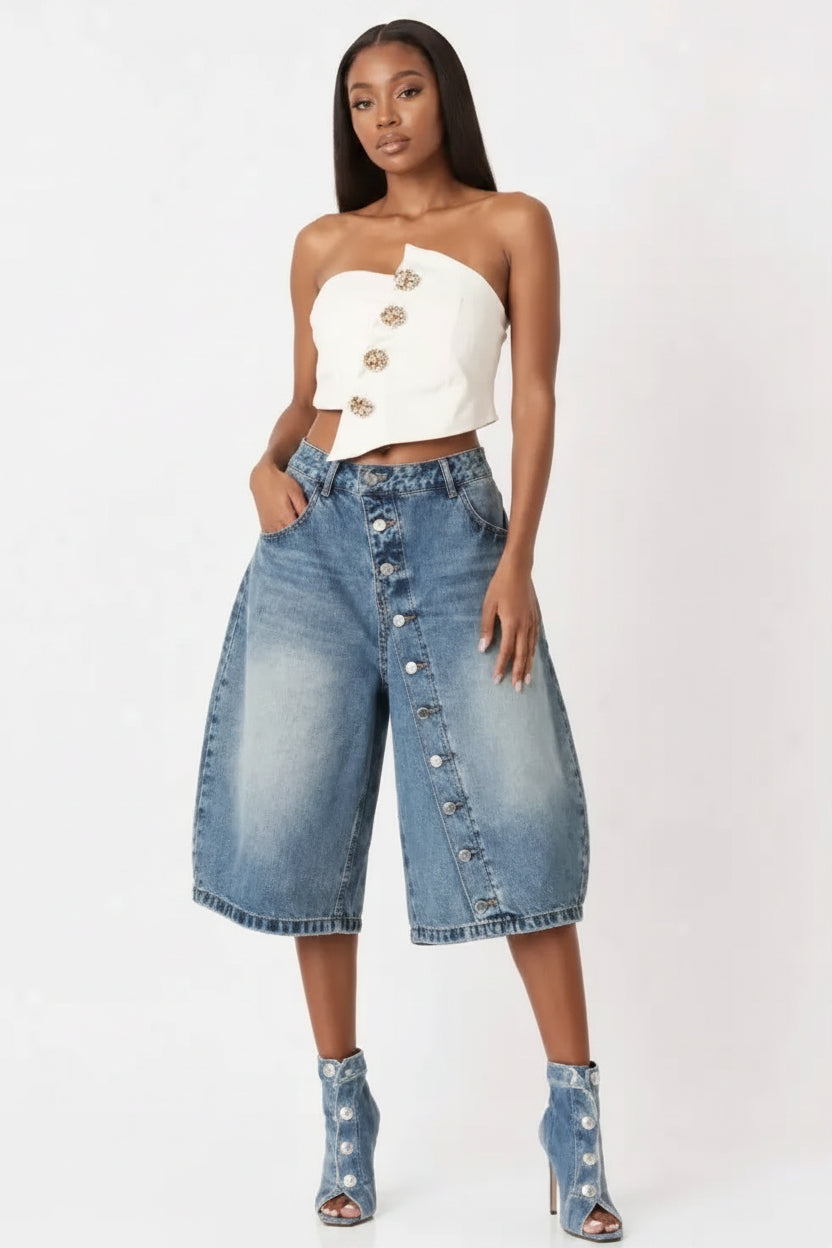 Woman wearing a white strapless top and blue denim culottes on a white background