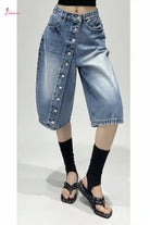 Person wearing a blue denim skirt with button details in an indoor setting.