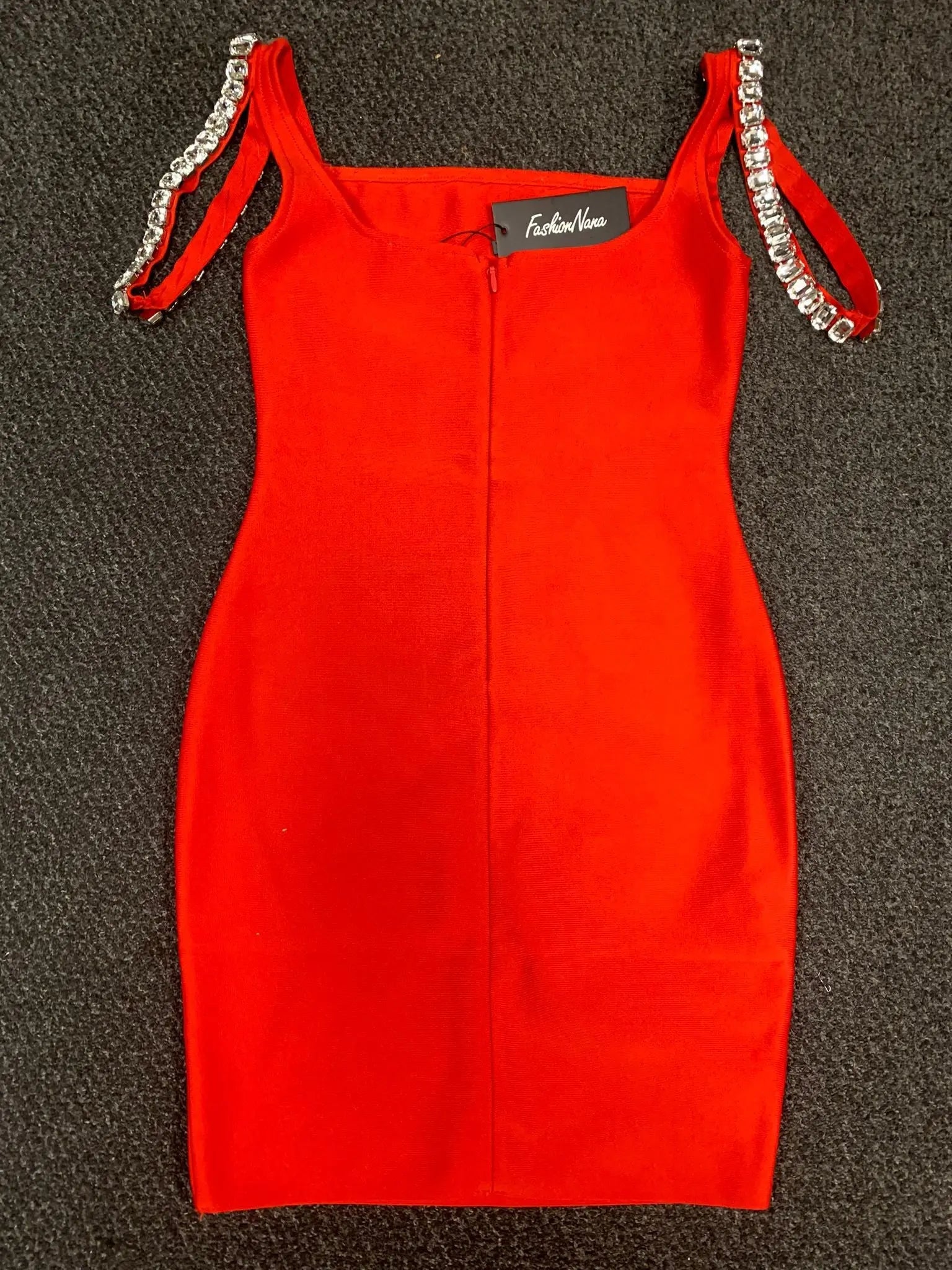 Red dress with chain straps on a textured black surface