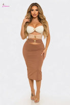 Woman wearing a beige two-piece outfit with a white top and brown skirt on a white background