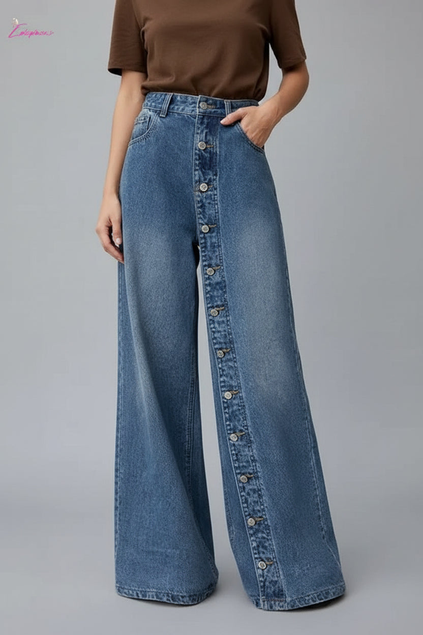Person wearing wide-leg jeans with a brown top against a white wall.
