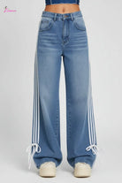 Person wearing blue jeans with white stripes on a train platform