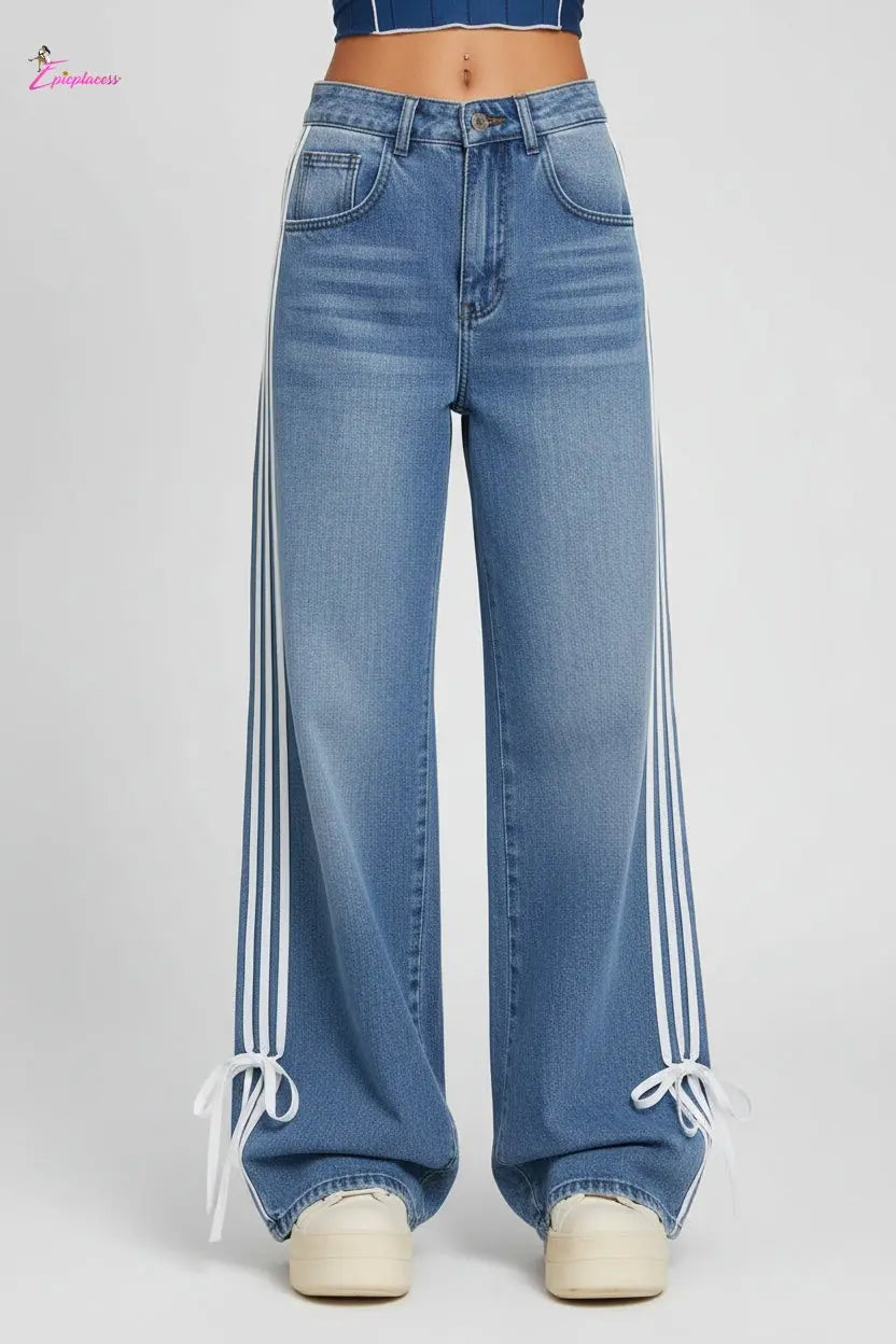 Person wearing blue jeans with white stripes on a train platform
