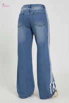 Person wearing blue jeans with white stripes standing on a platform.