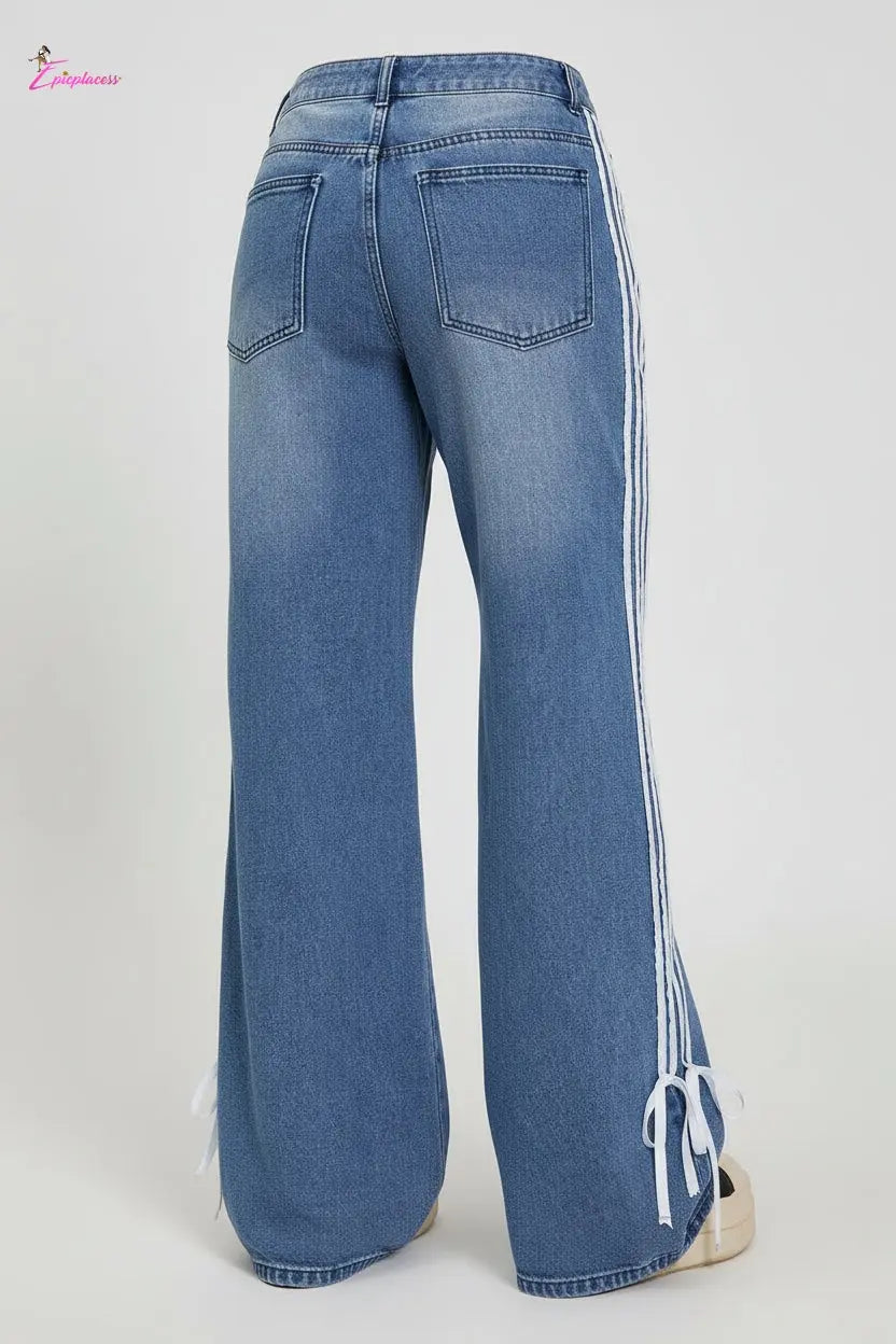 Person wearing blue jeans with white stripes standing on a platform.