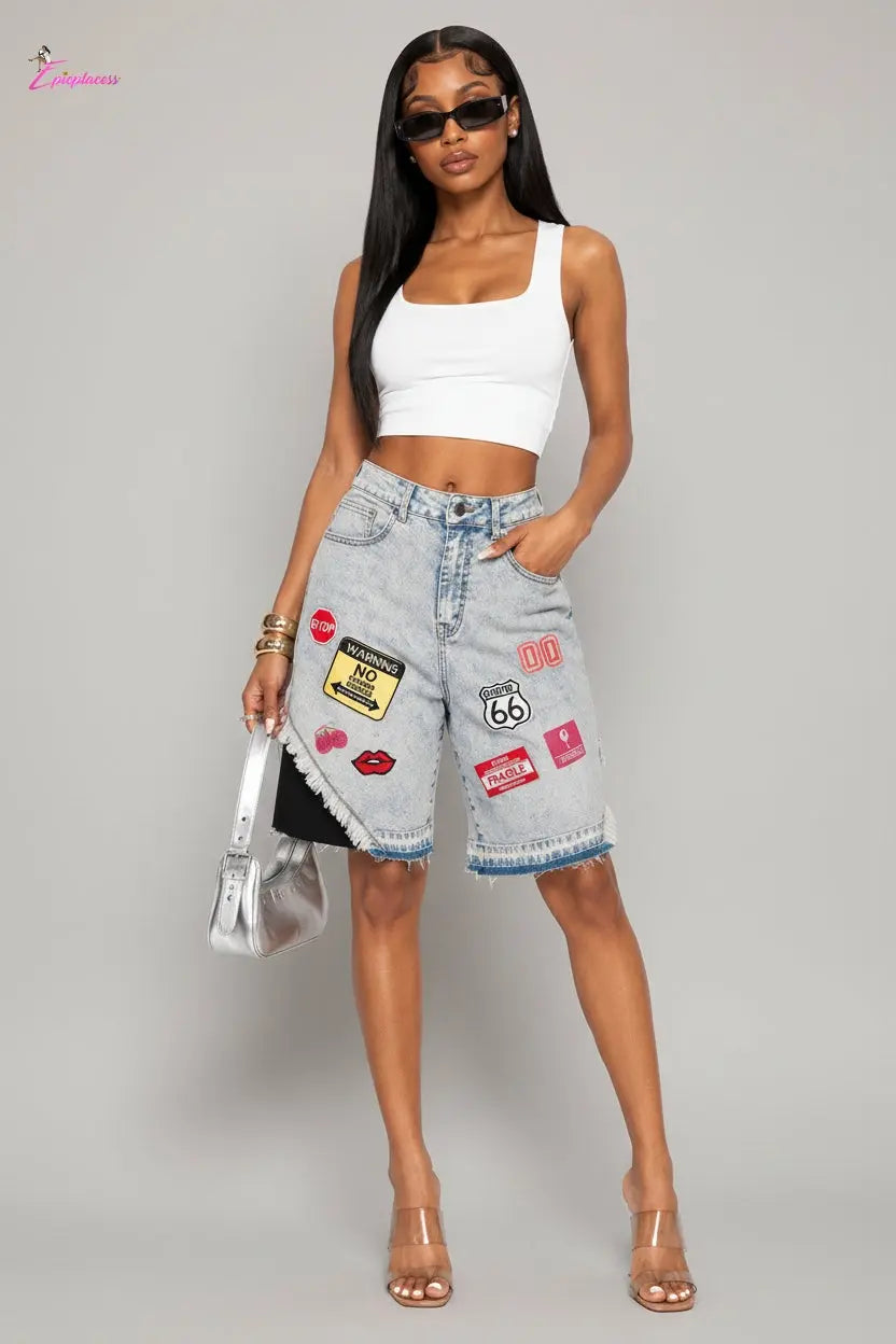 Woman wearing a white crop top and denim shorts with patches on a white background