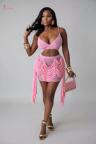 Woman in a pink outfit holding a matching handbag indoors.