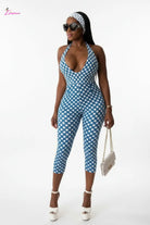 Model wearing retro polka dot halter jumpsuit in blue and white on white studio background
