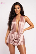Woman wearing a pink satin romper against a white background