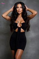 Woman wearing a black dress with cut-out design against a gray background