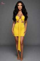 Woman wearing a yellow dress with cut-out design against a gray background