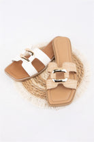 Pair of tan sandals with white straps on a white background