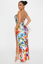 Studio professional back view of floral print maxi dress showing open back and side slit on white background